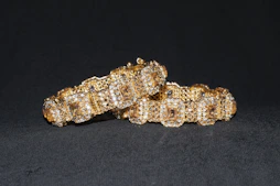 Close-up of elegant gold and silver bracelets displayed on a soft cream fabric background.
