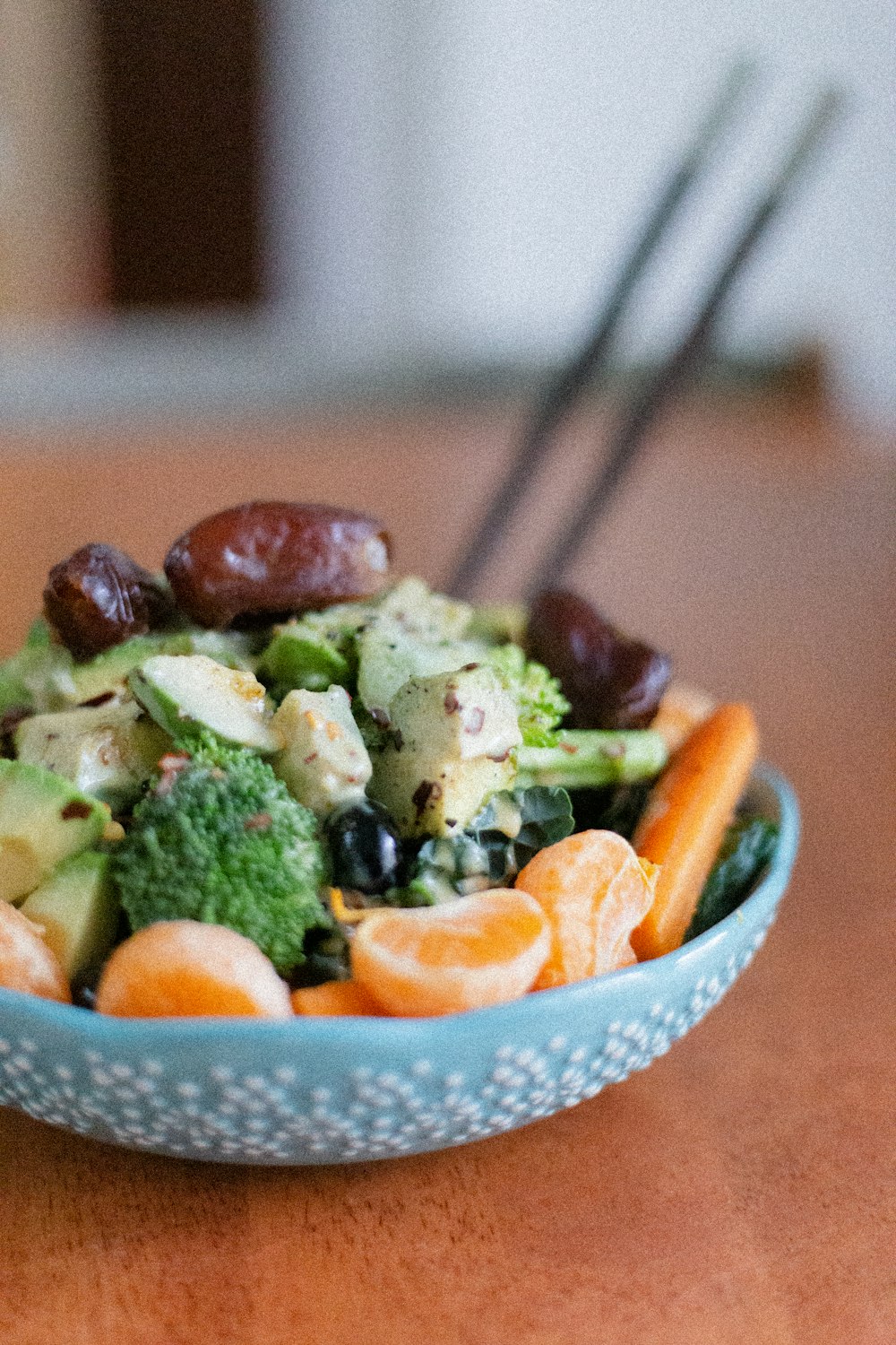 a blue bowl filled with broccoli, carrots and other vegetables