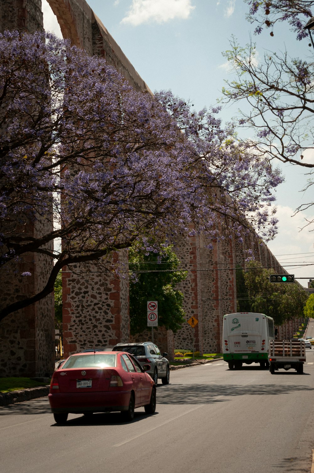 a red car driving down a street next to a tall brick building