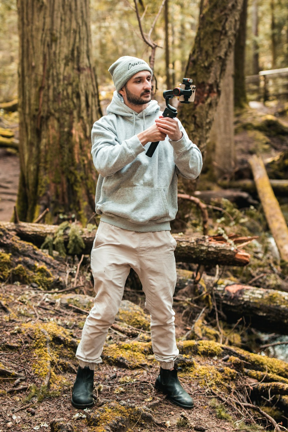 a man standing in the woods holding a camera