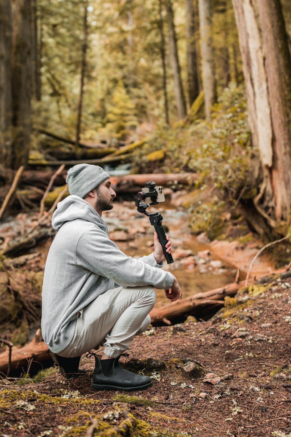 a man kneeling down in the woods with a camera