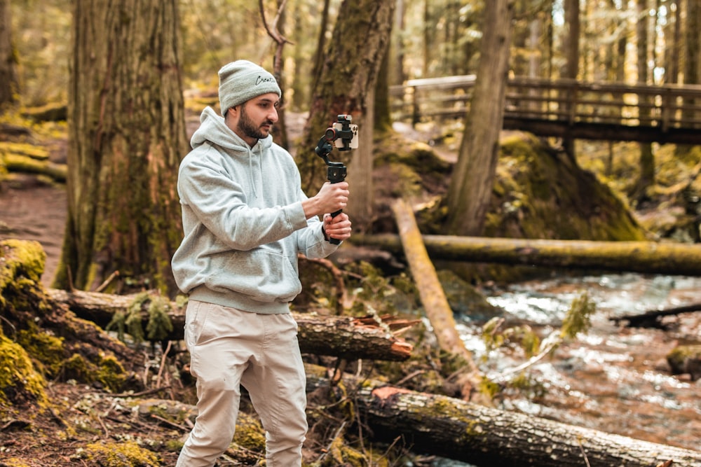 a man standing in the woods holding a camera