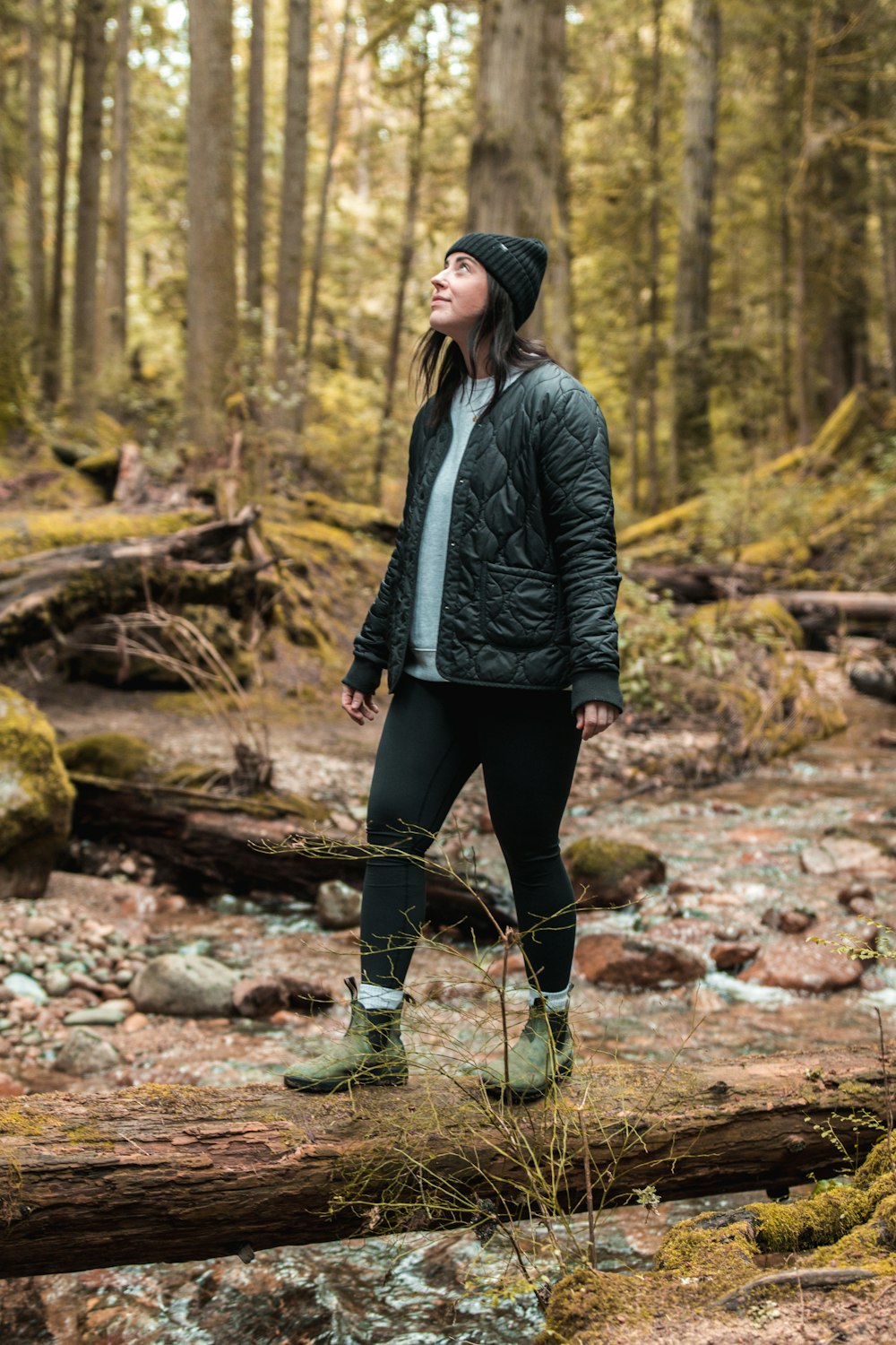 a woman standing on a log in the woods