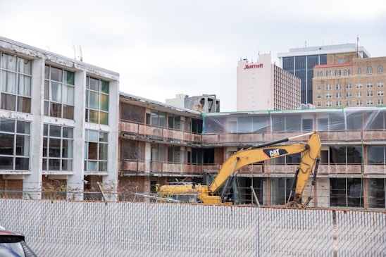 A construction site showing the demolition of an old building and the beginning of a new building's foundation.