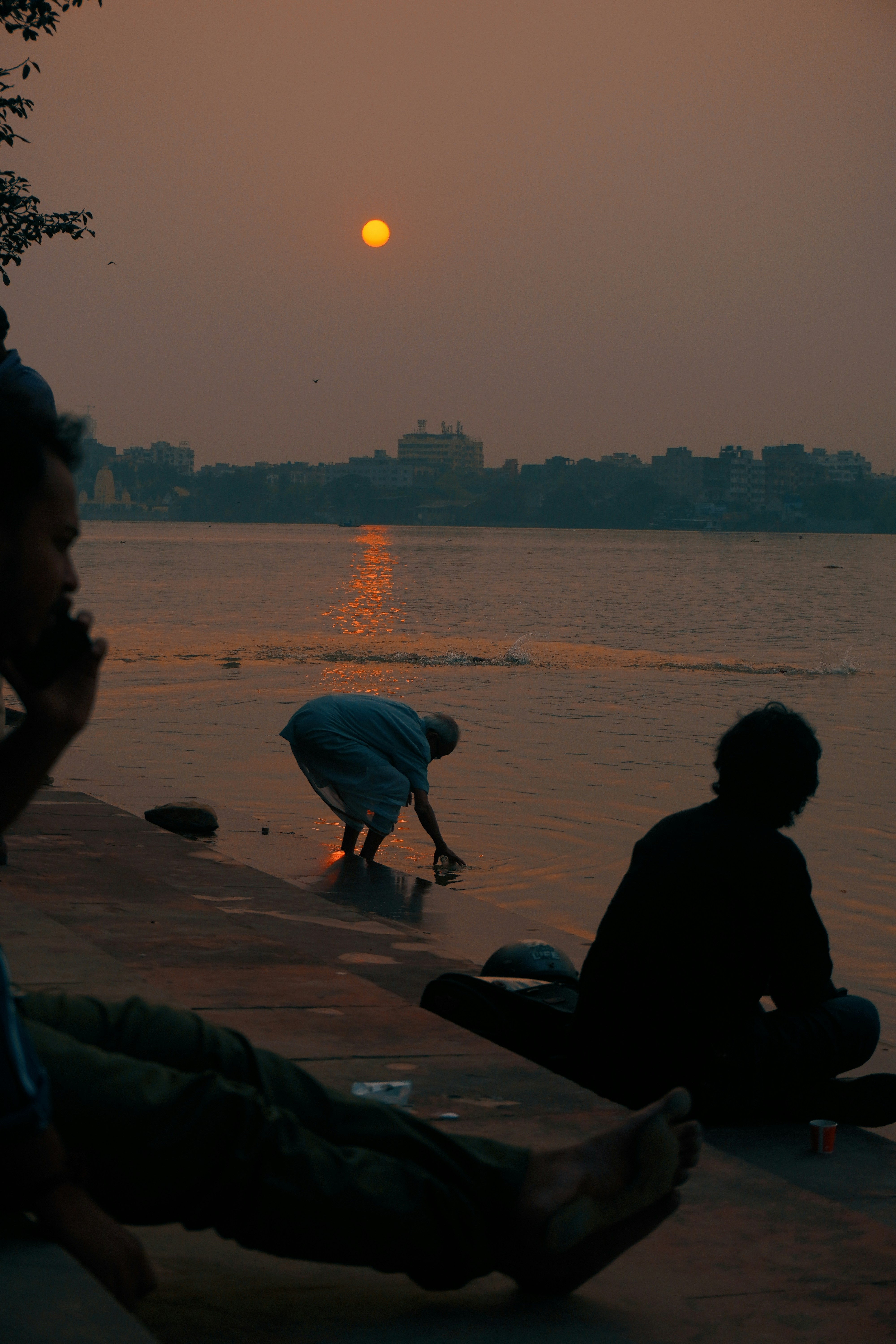 A group of people sitting on the edge of a body of water photo – Free ...