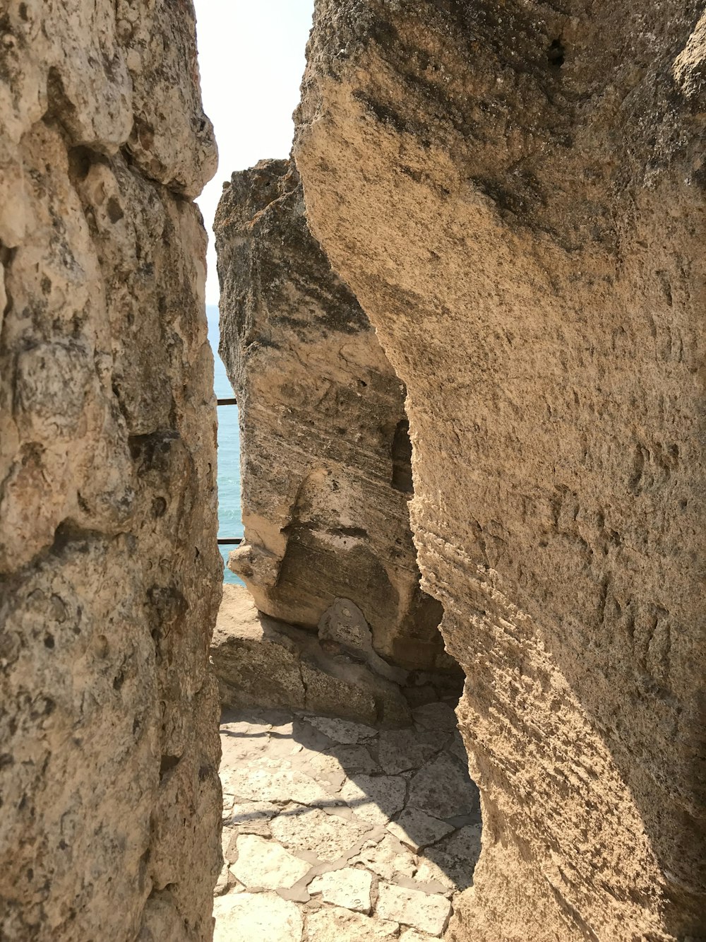 a stone walkway between two large rocks near the ocean