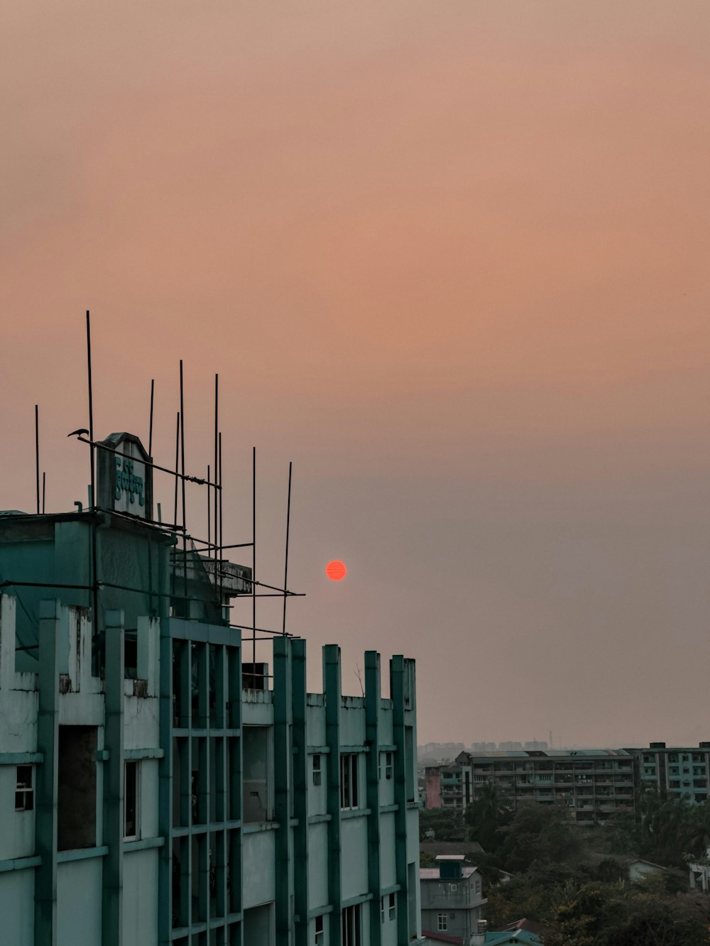 the sun is setting over a building with scaffolding