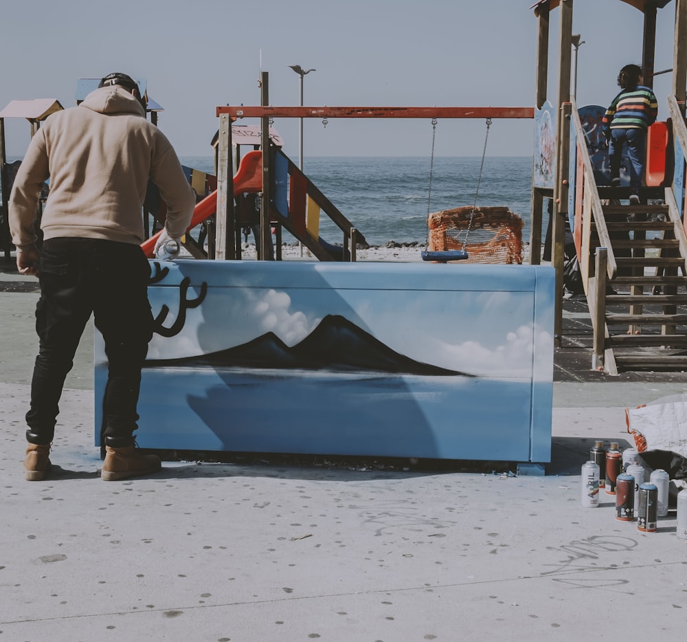 a man standing next to a painting of a mountain