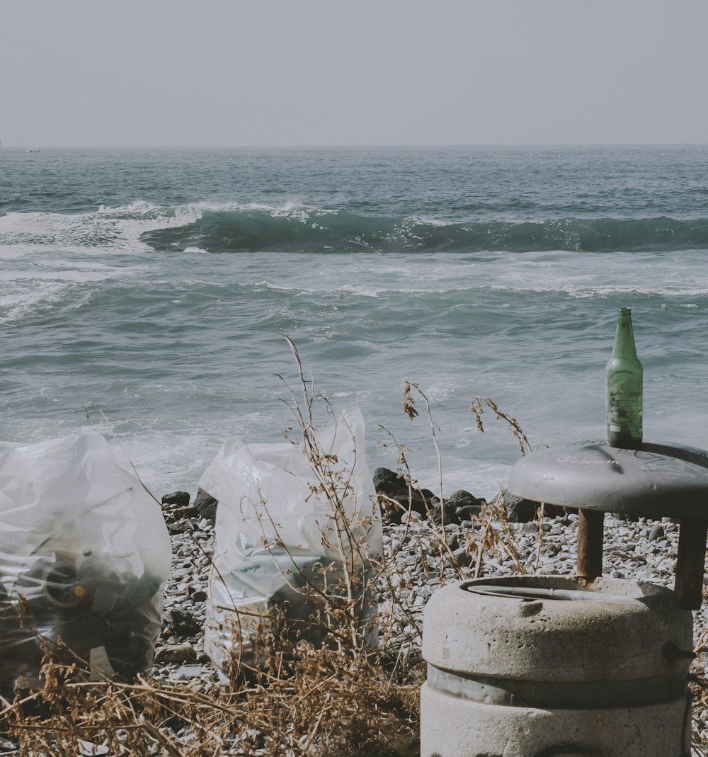 a trash can sitting on a beach next to the ocean