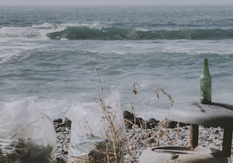 a trash can sitting on a beach next to the ocean