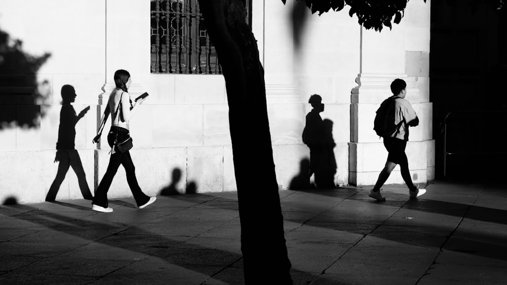 a group of people walking down a sidewalk next to a building