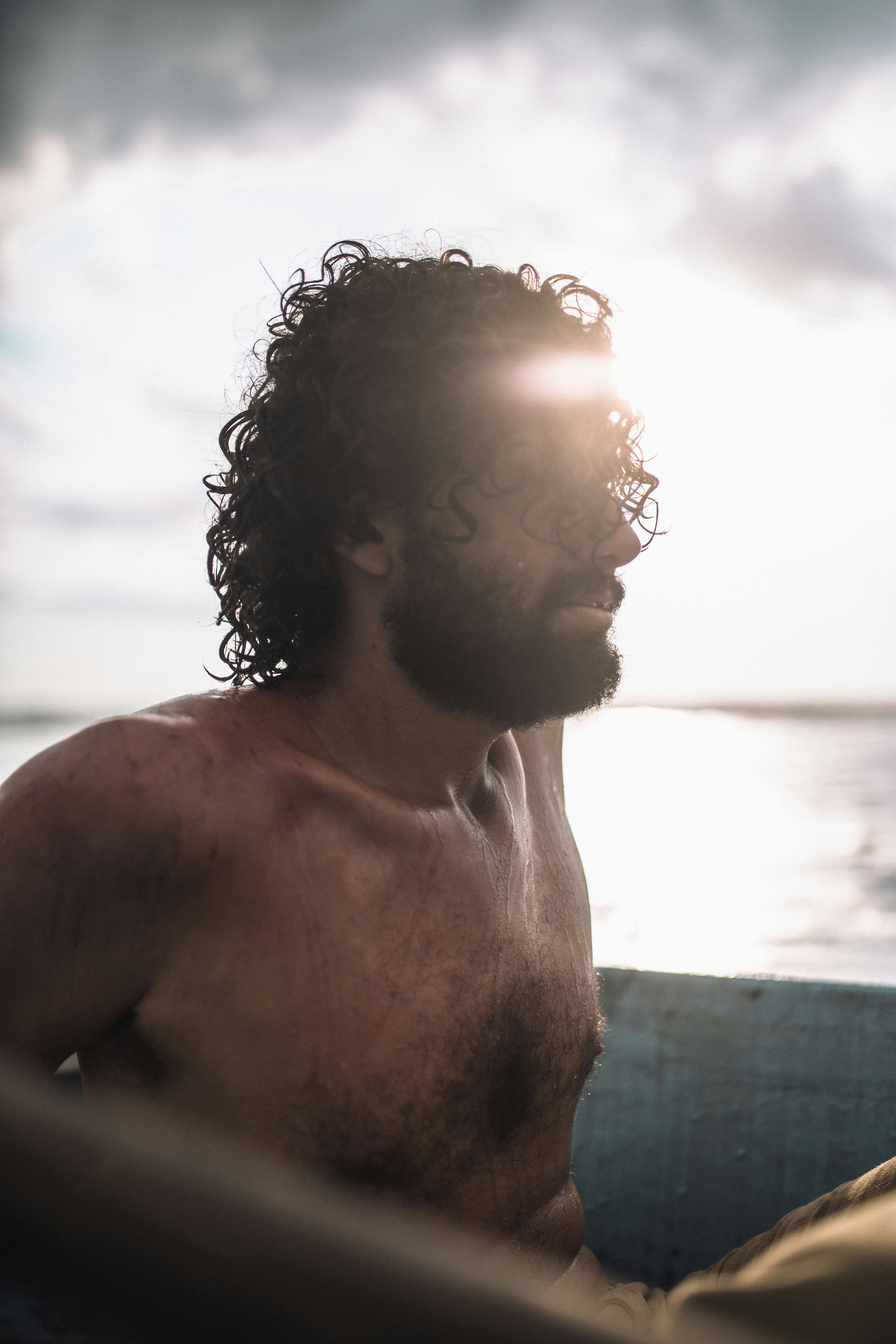 um homem sem camisa sentado em um barco no oceano
