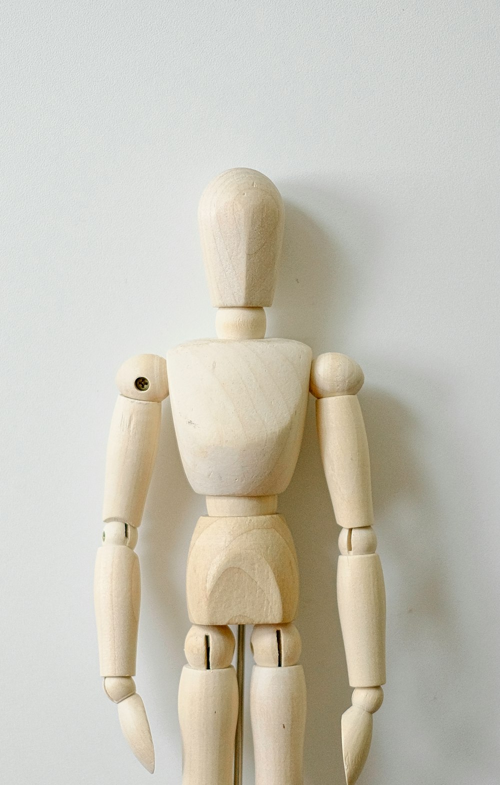 a wooden toy standing up against a white wall
