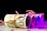 Several rolled bundles of euro banknotes are tied with twine, arranged in a row on a flat surface with a dark background. The lighting creates a gradient of purple and pink hues across the banknotes, adding a modern and abstract feel.