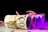 Several rolled bundles of euro banknotes are tied with twine, arranged in a row on a flat surface with a dark background. The lighting creates a gradient of purple and pink hues across the banknotes, adding a modern and abstract feel.