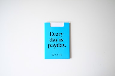 A blue card with the phrase 'Every day is payday.' printed in bold black letters. The card also has a GoDaddy logo at the bottom.