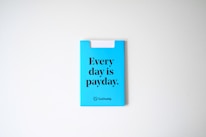 A blue card with the phrase 'Every day is payday.' printed in bold black letters. The card also has a GoDaddy logo at the bottom.