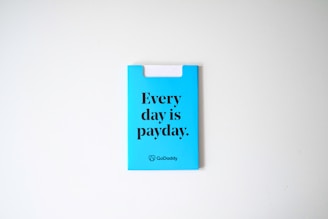 A blue card with the phrase 'Every day is payday.' printed in bold black letters. The card also has a GoDaddy logo at the bottom.