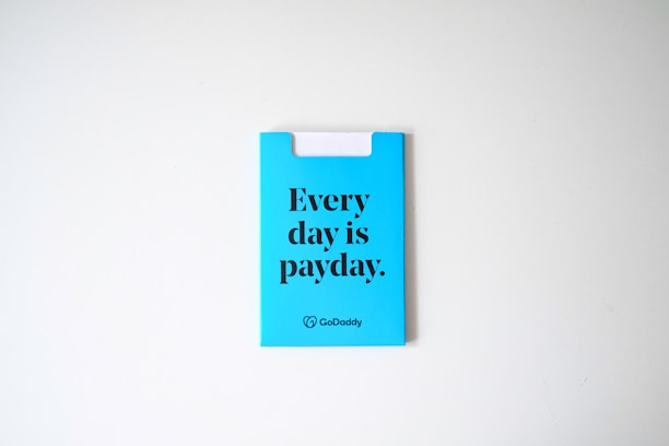 A blue card with the phrase 'Every day is payday.' printed in bold black letters. The card also has a GoDaddy logo at the bottom.