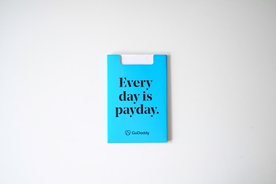 A blue card with the phrase 'Every day is payday.' printed in bold black letters. The card also has a GoDaddy logo at the bottom.