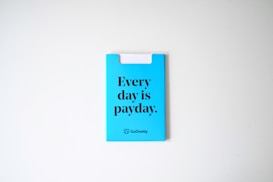 A blue card with the phrase 'Every day is payday.' printed in bold black letters. The card also has a GoDaddy logo at the bottom.