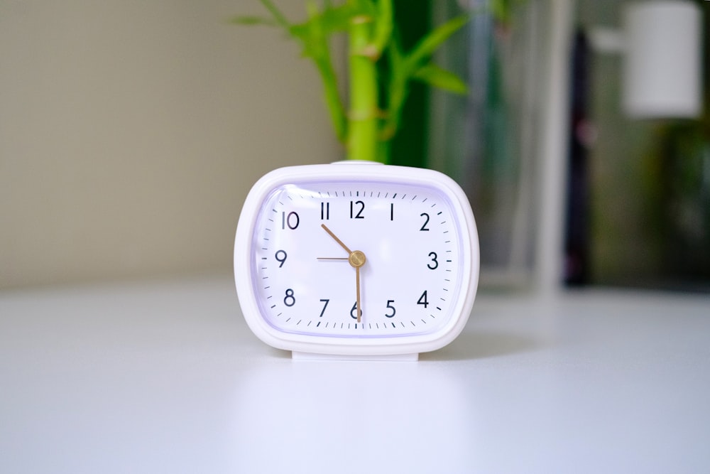 a white clock sitting on top of a white table