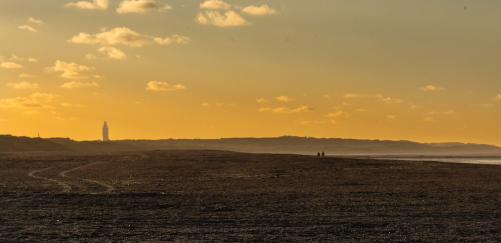 a couple of people walking on a beach at sunset