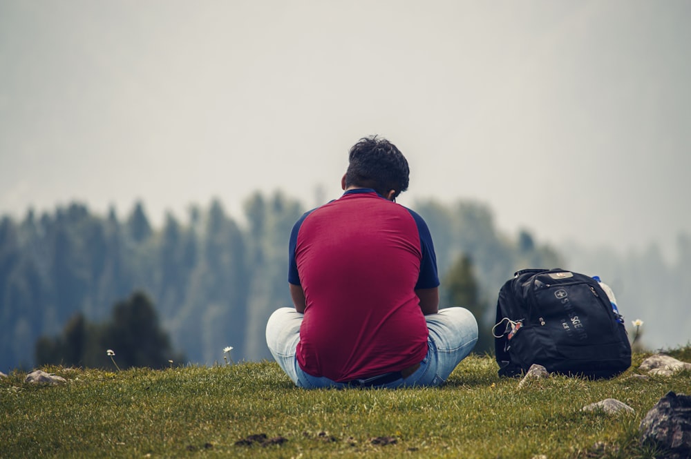 a person sitting on a hill with a backpack