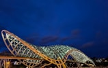 A sleek steel bridge structure illuminated at dusk, showcasing intricate engineering details.