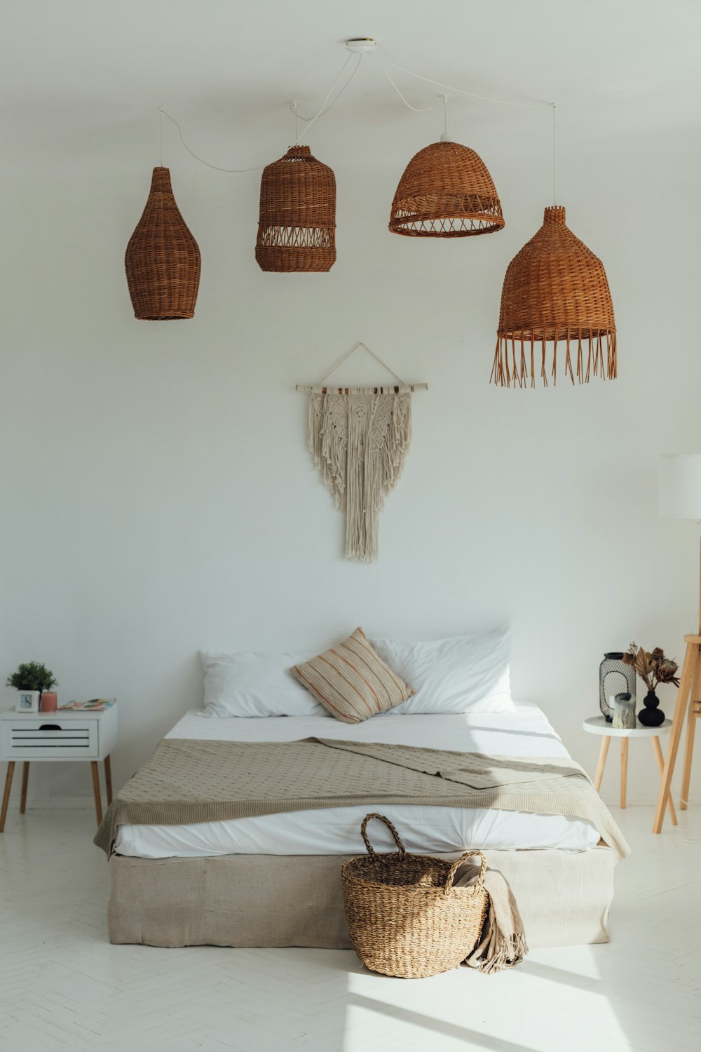 a bedroom with a bed, lamps and a basket on the floor