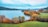 A serene autumn landscape with fallen leaves and a calm lake.