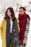 A group of women in different winter coats, laughing together in a winter park.