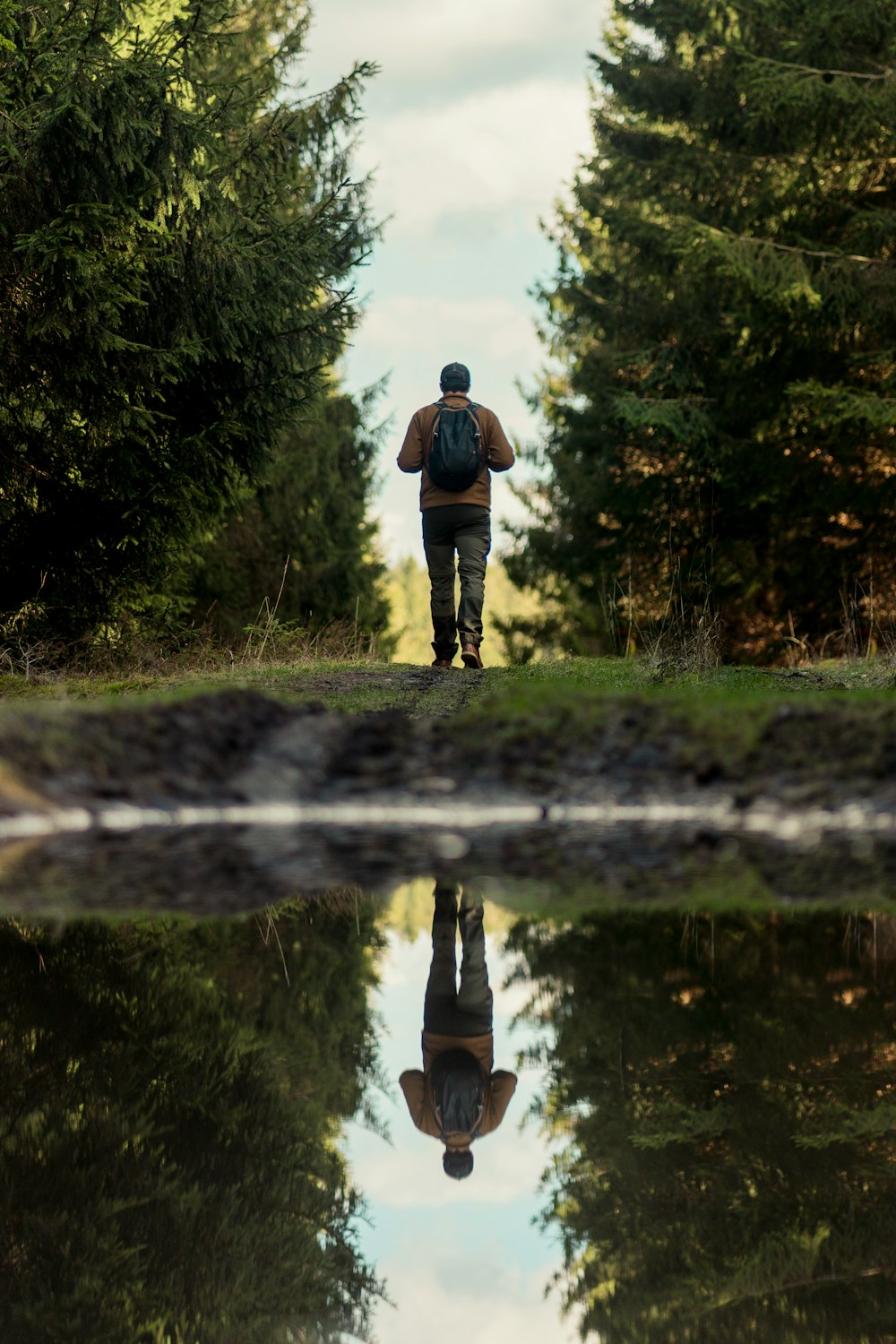 Un homme marchant sur un chemin de terre à côté d’une forêt