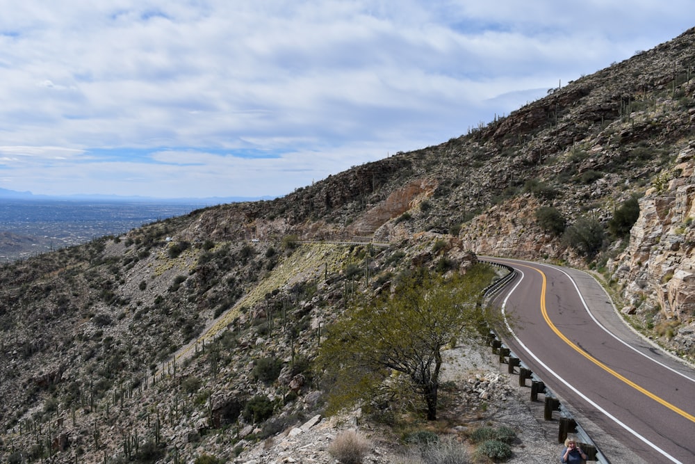 two people sitting on a bench on the side of a mountain