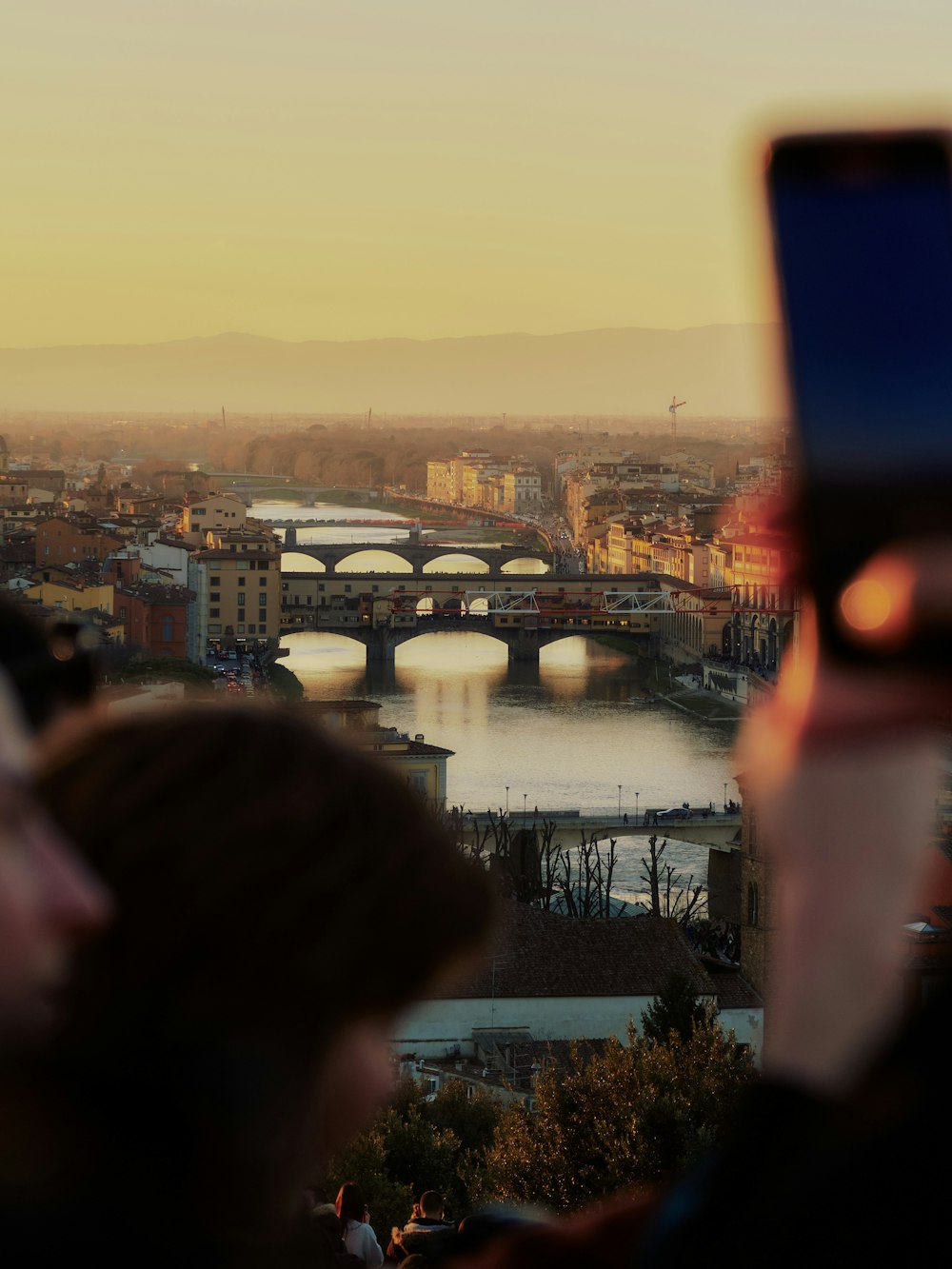 a person taking a picture of a bridge over a river