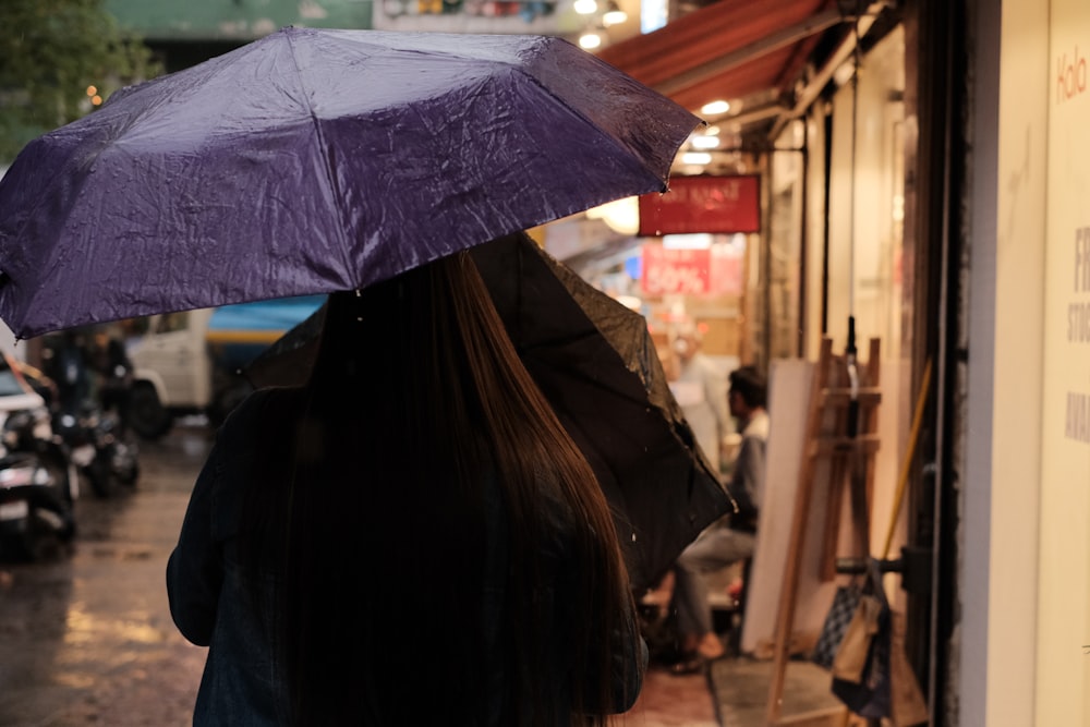 a woman walking down a street holding a purple umbrella