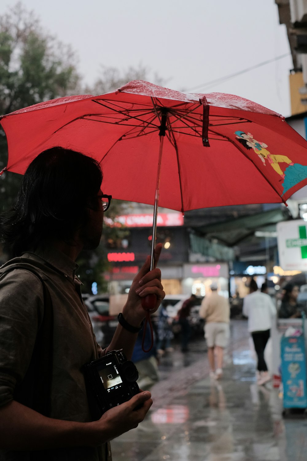 Un hombre sosteniendo un paraguas rojo bajo la lluvia