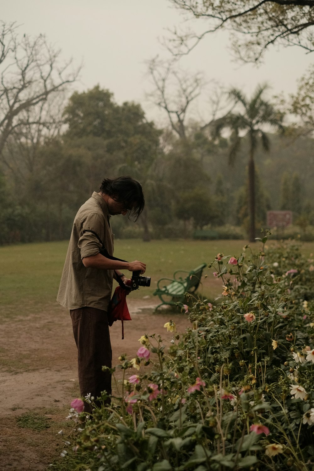 a man holding a camera in a field of flowers