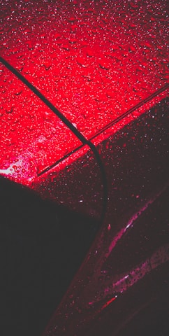 a red car with rain drops on it
