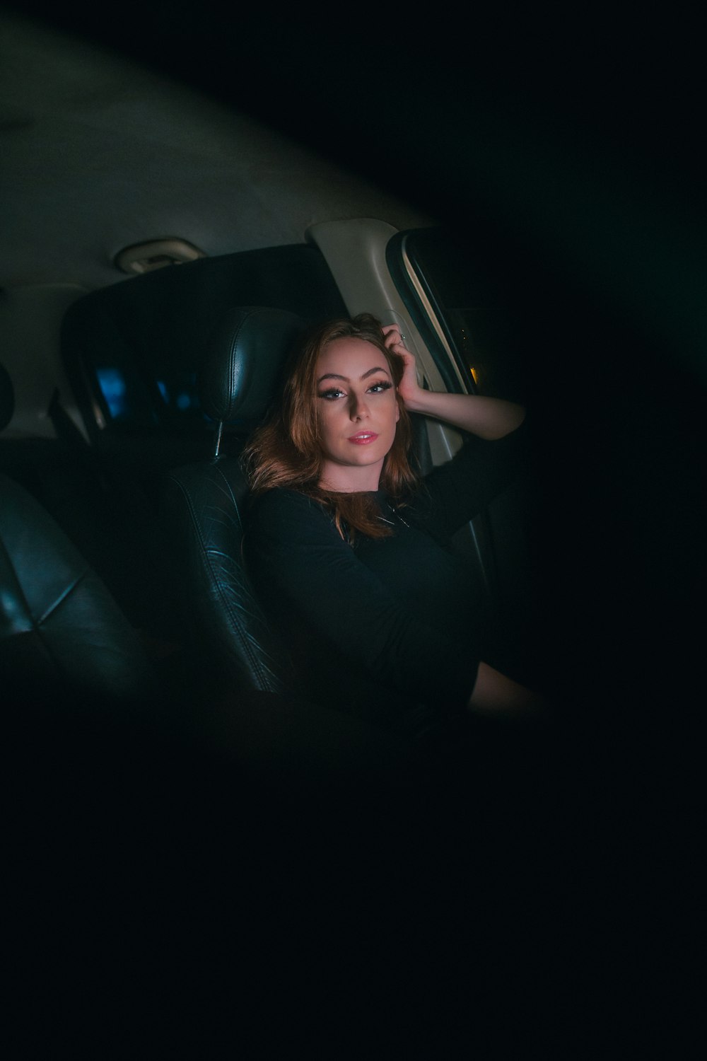 a woman sitting in a car with her hand on her head