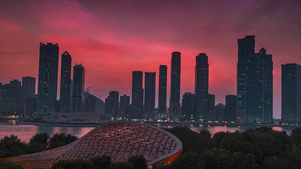 a city skyline with a red sky in the background