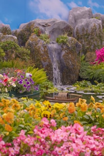 a waterfall in the middle of a garden filled with flowers