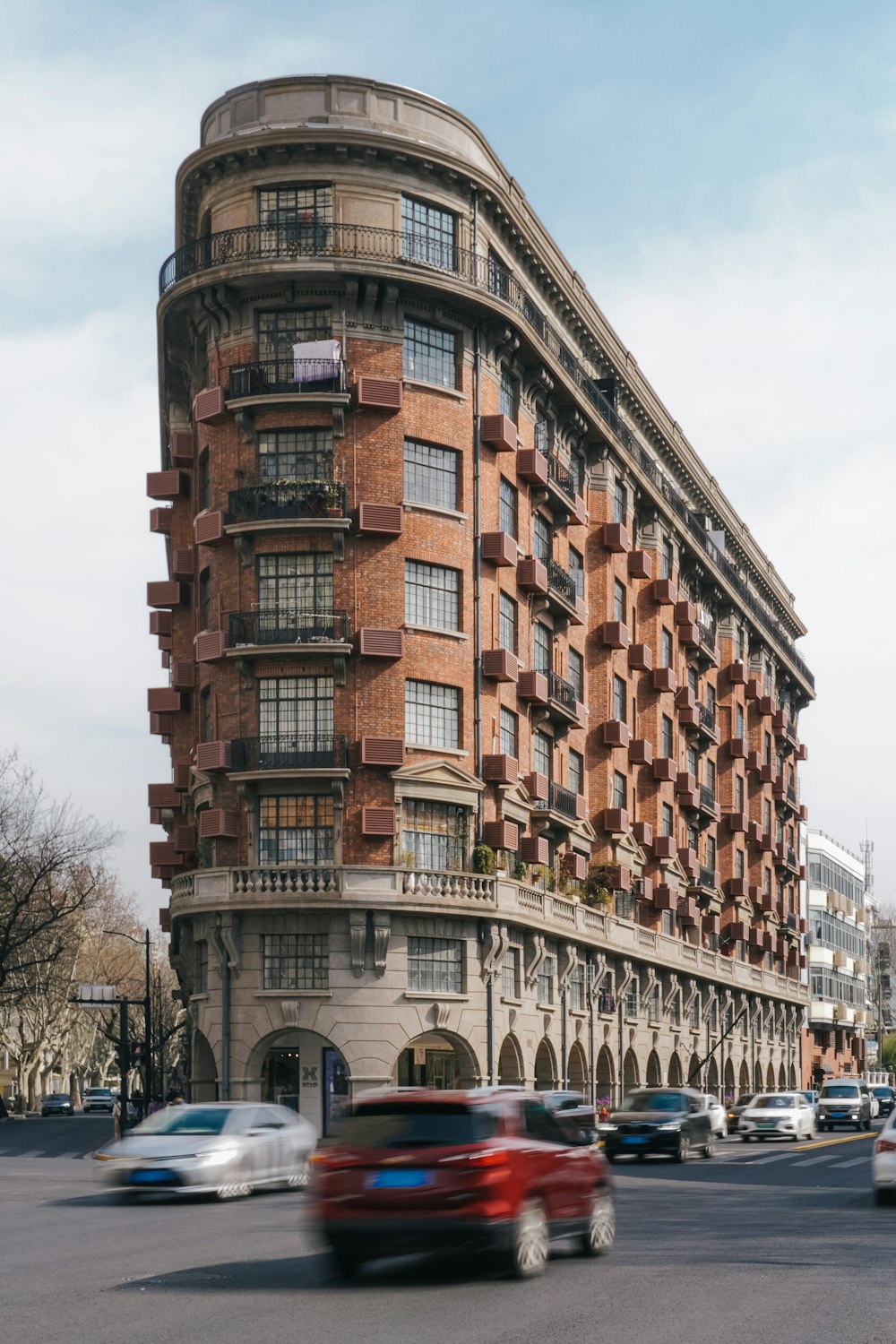 a red car driving down a street next to a tall building