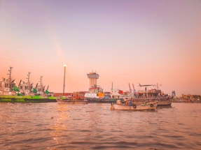 Photo of the Santos port at sunset with calm waters and docked ships.