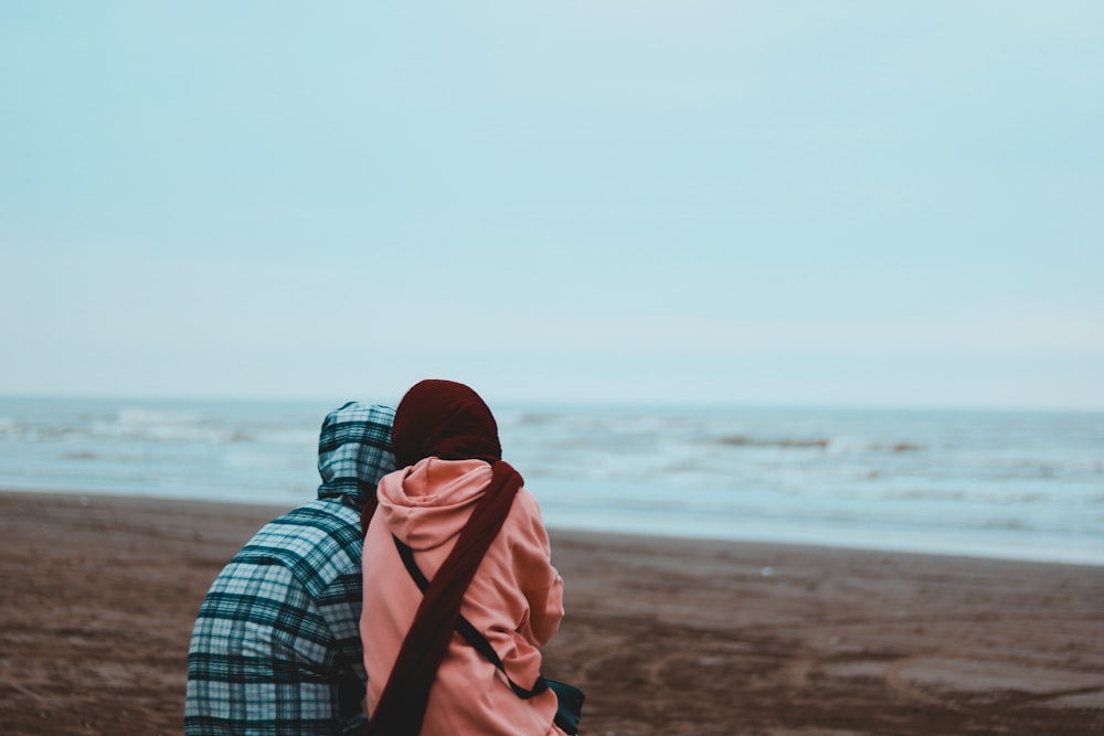 Dos personas sentadas en una playa frente al océano