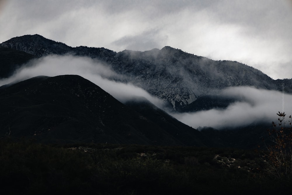 a mountain covered in low lying clouds under a cloudy sky