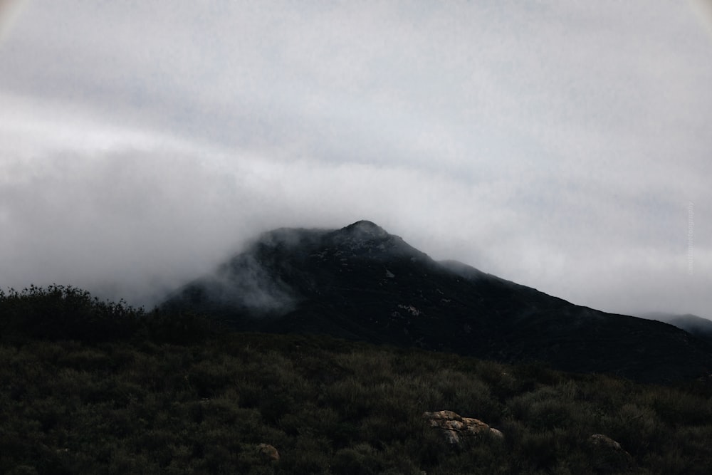 Une montagne couverte de nuages avec un arc-en-ciel dans le ciel