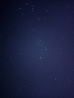 A dark, starry night sky with numerous small, twinkling stars scattered across the expanse. The image captures the vastness and mystery of the cosmos.