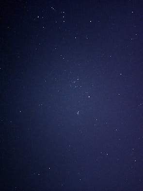 A dark, starry night sky with numerous small, twinkling stars scattered across the expanse. The image captures the vastness and mystery of the cosmos.