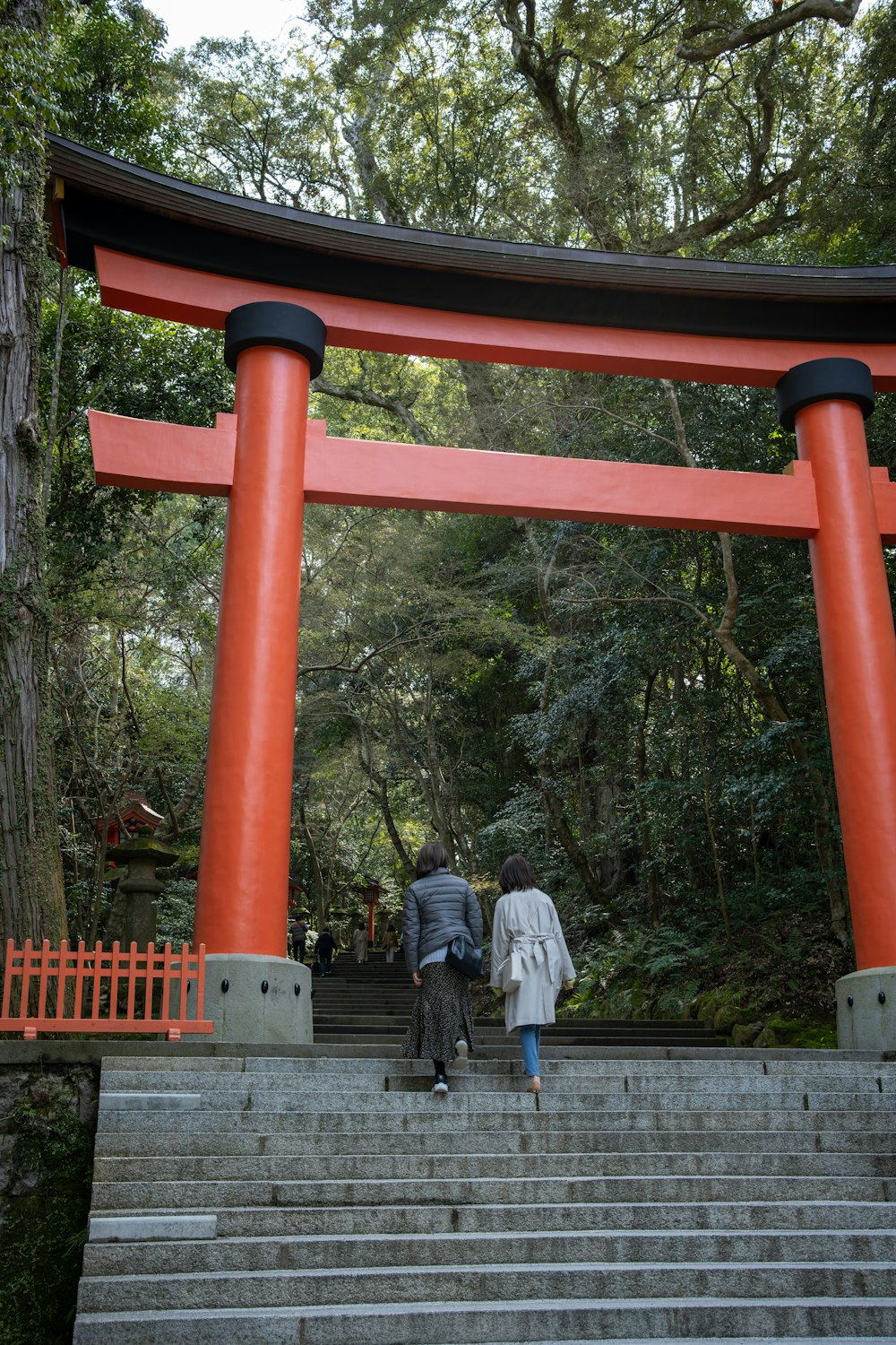 two people walking up a flight of stairs in front of a red tori tori tori